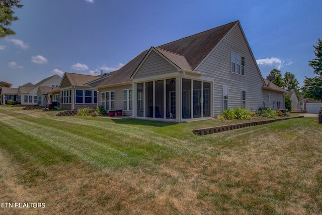 rear view of property with a lawn, a sunroom, and a garage