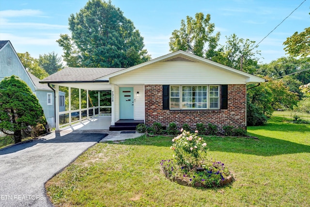 view of front of property featuring an attached carport, a front yard, brick siding, and aphalt driveway