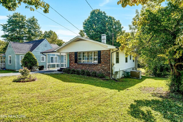 view of front of house with central AC unit and a front yard