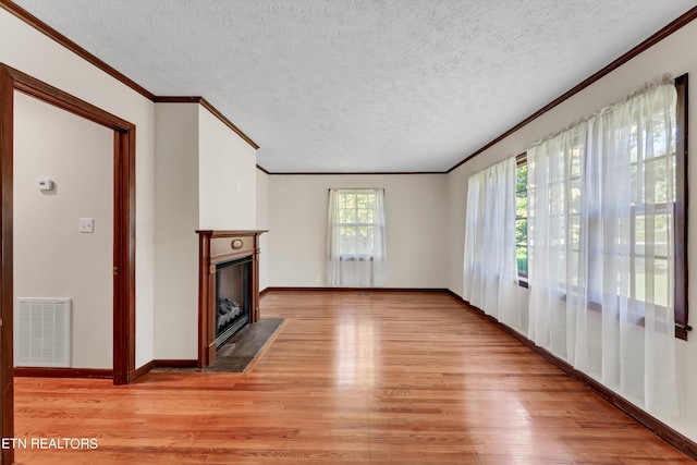 unfurnished living room with visible vents, a fireplace with flush hearth, ornamental molding, a textured ceiling, and light wood-style floors