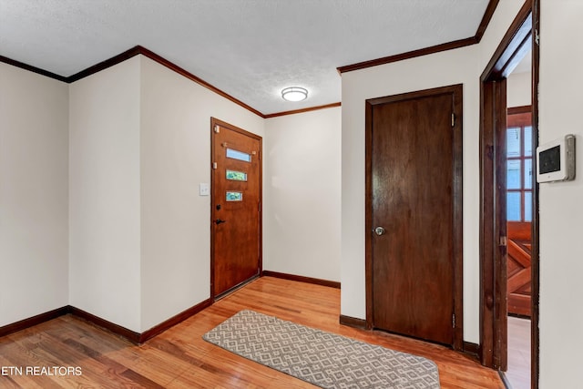 foyer entrance featuring a textured ceiling, baseboards, and light wood-style floors