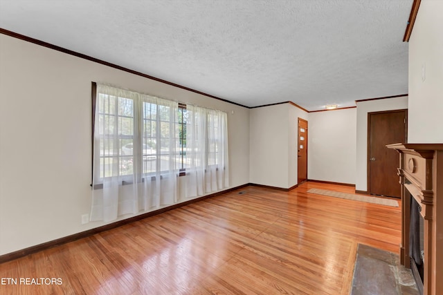 unfurnished living room with a fireplace with flush hearth, light wood-type flooring, crown molding, and a textured ceiling