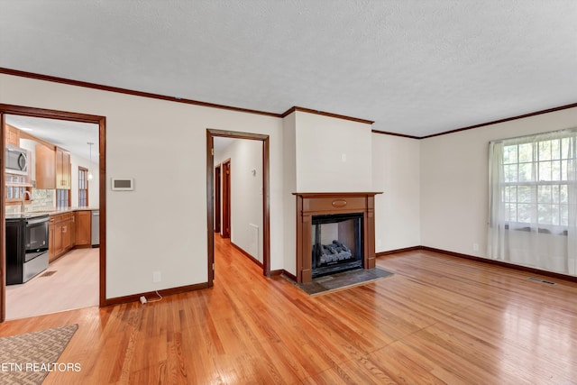 unfurnished living room with baseboards, a fireplace, visible vents, and light wood-style floors