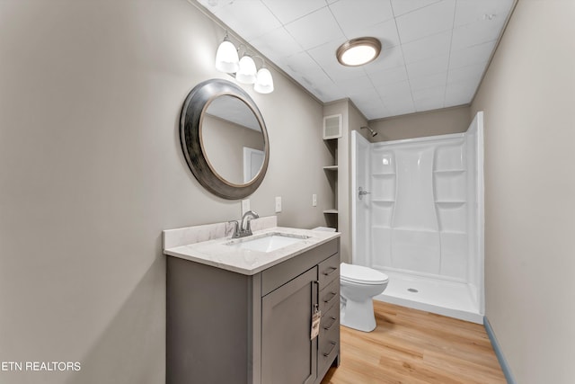 bathroom with a stall shower, visible vents, toilet, wood finished floors, and vanity