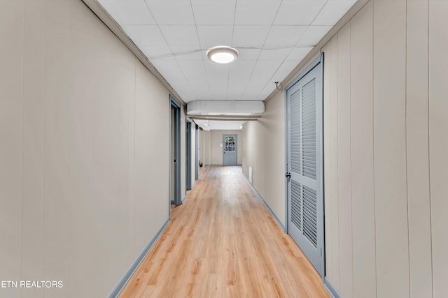 corridor with a paneled ceiling and light wood-style floors