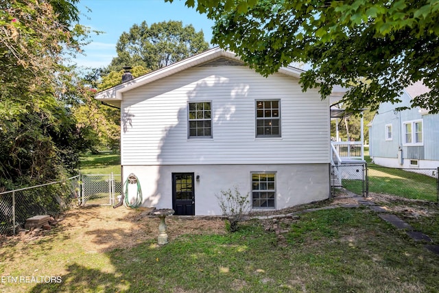 back of house with a gate, a fenced backyard, and a lawn