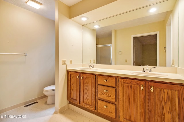 bathroom with tile patterned flooring, a shower with shower door, vanity, and toilet