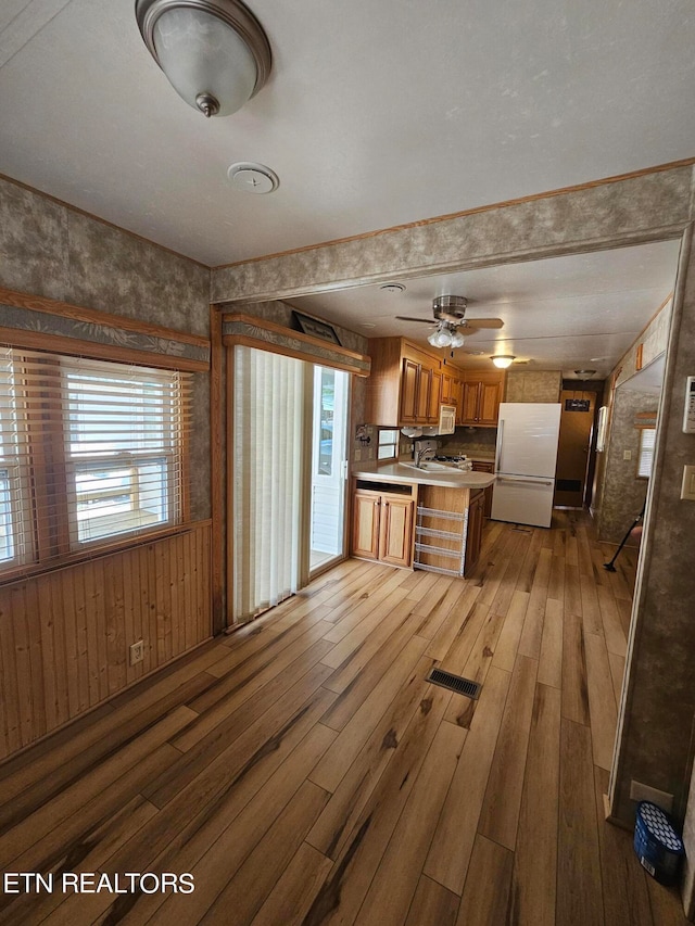 kitchen featuring kitchen peninsula, light wood-type flooring, white appliances, and ceiling fan