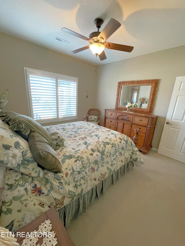 bedroom with light colored carpet, visible vents, and ceiling fan