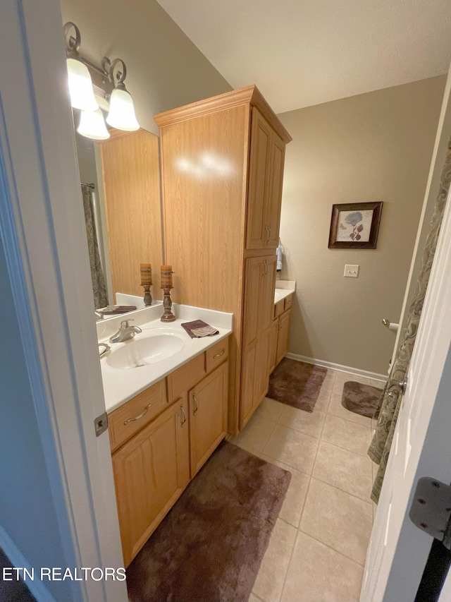 full bath with tile patterned flooring, baseboards, and vanity