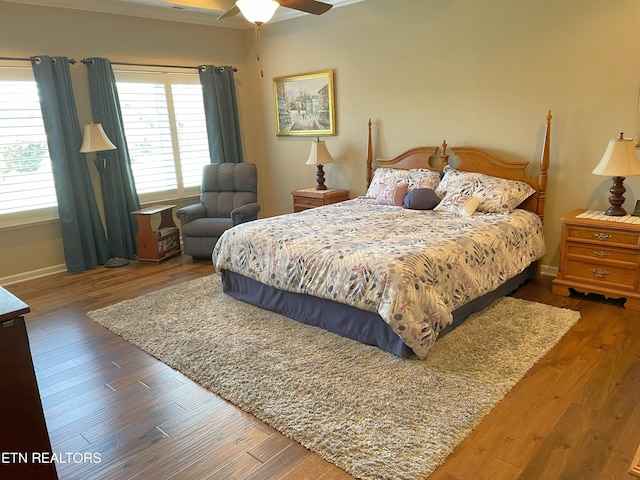 bedroom with ceiling fan, baseboards, and wood finished floors