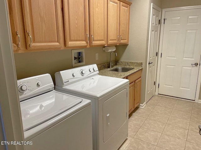 washroom with light tile patterned floors, washer and clothes dryer, a sink, and cabinet space