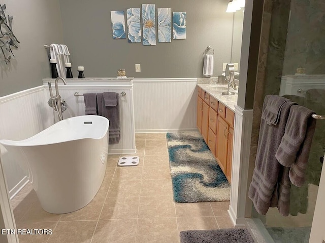 full bath featuring a soaking tub, wainscoting, and tile patterned floors