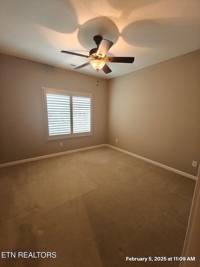 carpeted spare room featuring ceiling fan, visible vents, and baseboards