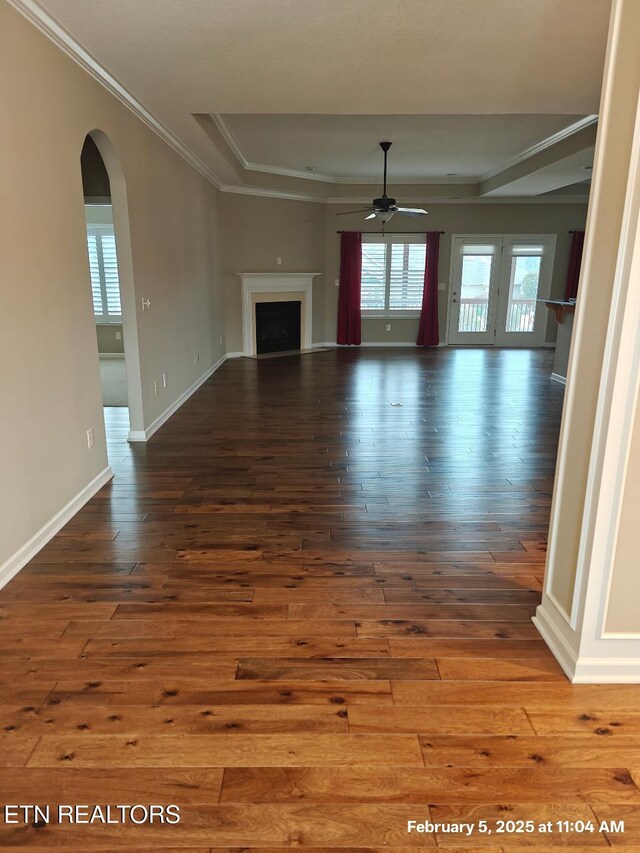 unfurnished living room featuring wood-type flooring, ornamental molding, and ceiling fan