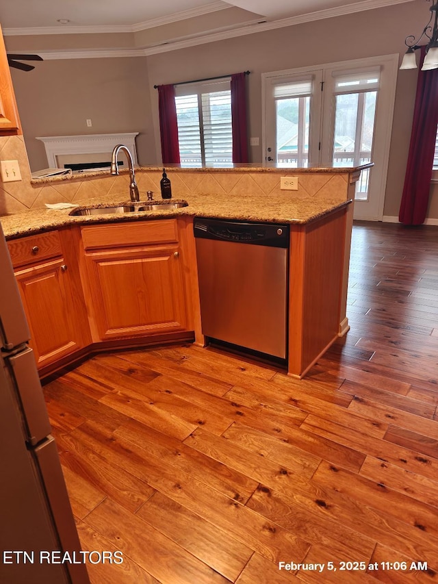 kitchen featuring decorative backsplash, light wood-type flooring, dishwasher, and a sink