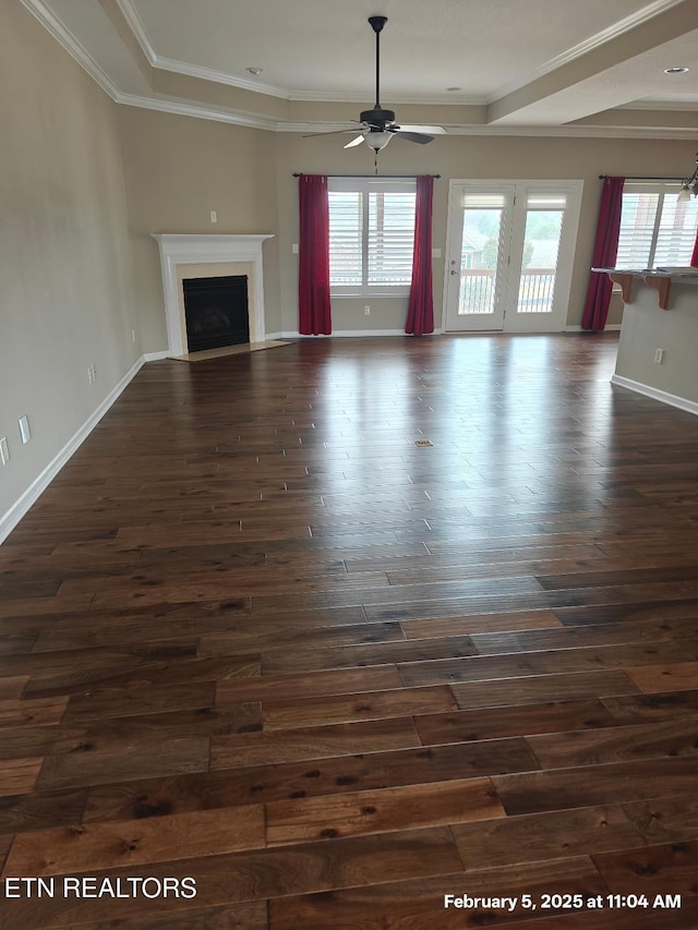 unfurnished living room with ceiling fan, dark wood-type flooring, a fireplace, baseboards, and ornamental molding