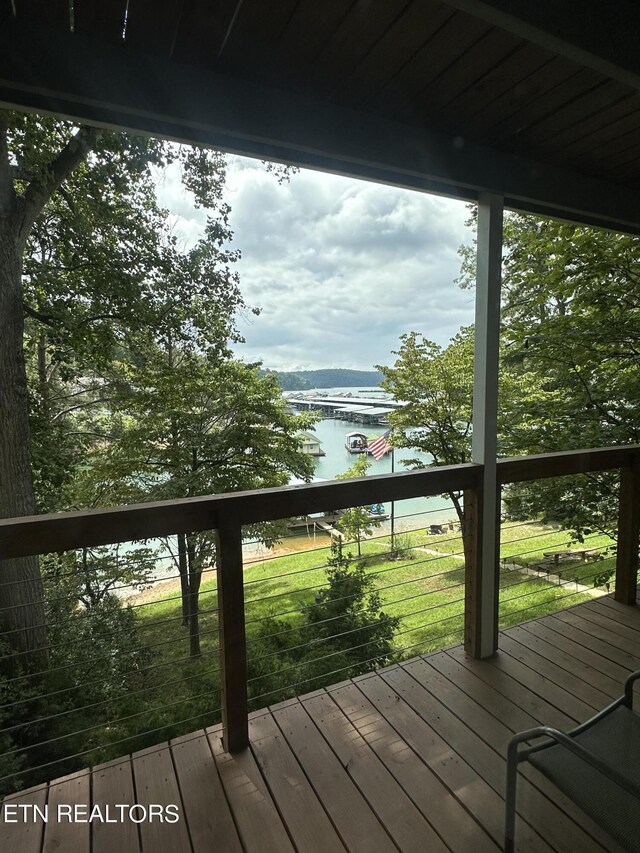 wooden terrace with a water view and a yard