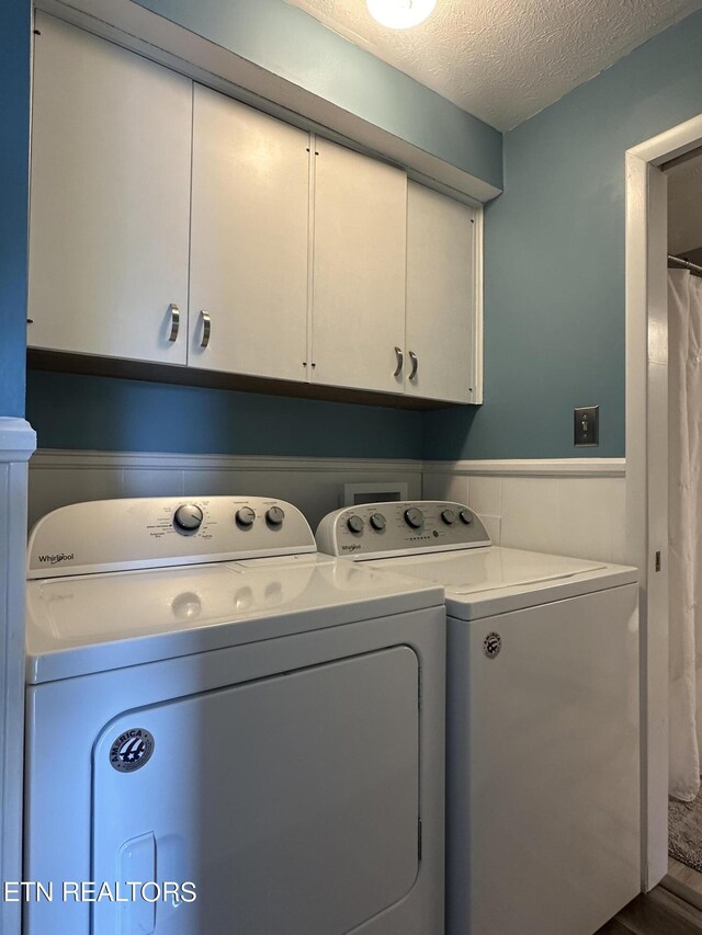 clothes washing area featuring separate washer and dryer, a textured ceiling, hardwood / wood-style flooring, and cabinets