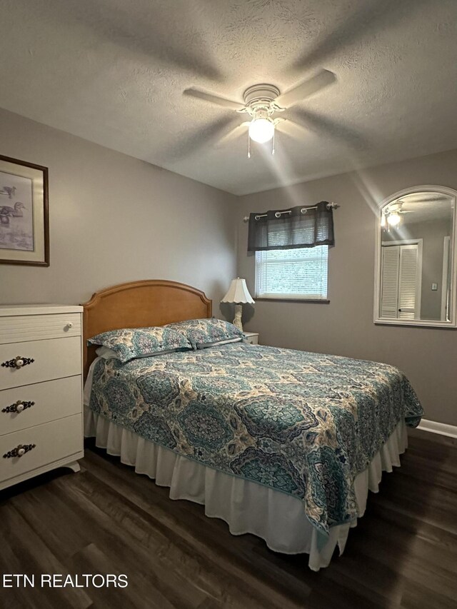 bedroom with a textured ceiling, ceiling fan, and dark hardwood / wood-style flooring