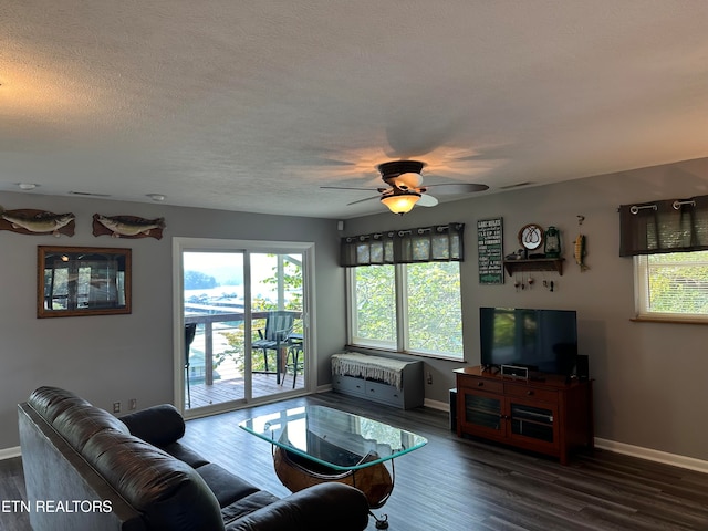 living room with a textured ceiling, ceiling fan, and dark hardwood / wood-style floors