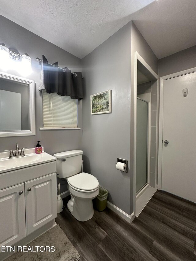 bathroom featuring a textured ceiling, vanity, an enclosed shower, toilet, and hardwood / wood-style flooring