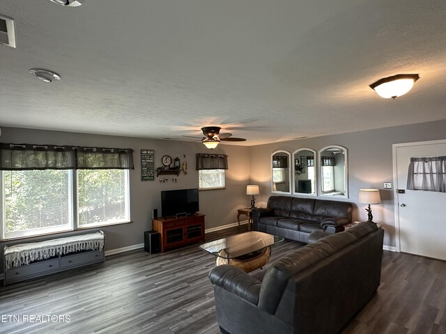 living room with dark wood-type flooring, a textured ceiling, and ceiling fan