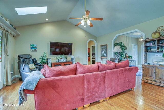 living room with light wood-type flooring, ceiling fan, and lofted ceiling with skylight