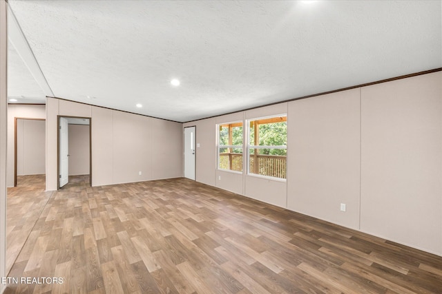 spare room featuring recessed lighting, light wood-style flooring, a textured ceiling, and crown molding