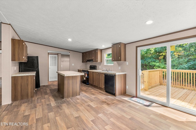 kitchen with wood finished floors, a kitchen island, black appliances, vaulted ceiling, and light countertops