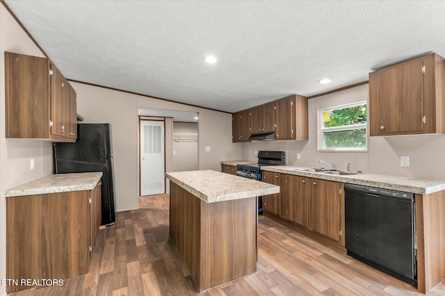 kitchen featuring black appliances, under cabinet range hood, wood finished floors, a center island, and light countertops