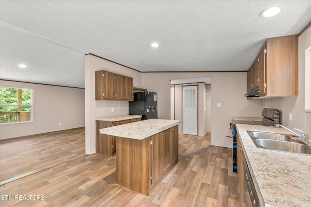 kitchen featuring light wood finished floors, a kitchen island, light countertops, brown cabinets, and appliances with stainless steel finishes