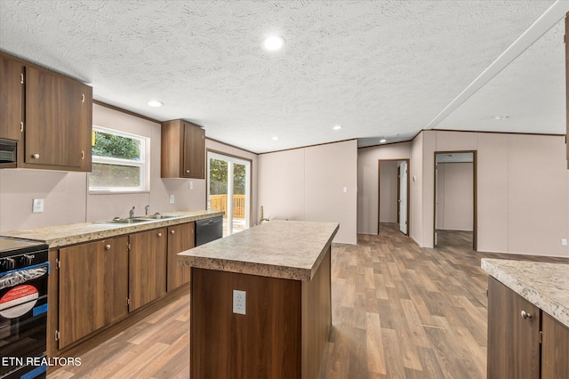 kitchen featuring a sink, a kitchen island, black appliances, and light wood finished floors