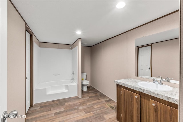 full bathroom with a tub, toilet, recessed lighting, wood finished floors, and vanity