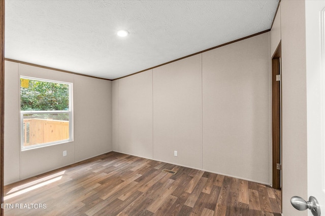 unfurnished room featuring crown molding, wood finished floors, and a textured ceiling