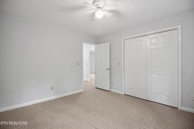 unfurnished bedroom featuring light carpet, a textured ceiling, ceiling fan, and a closet