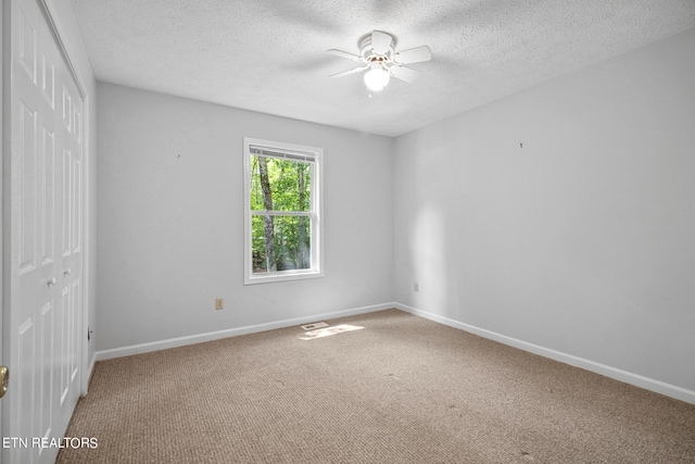 carpeted spare room featuring a textured ceiling and ceiling fan