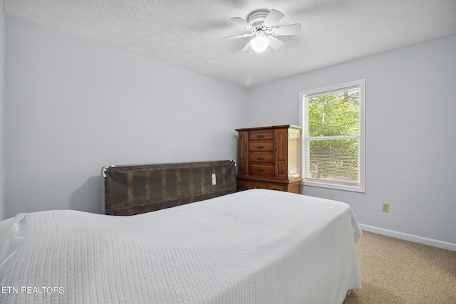 carpeted bedroom with ceiling fan and a textured ceiling