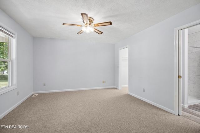 carpeted empty room featuring ceiling fan and a textured ceiling