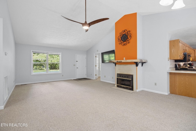 unfurnished living room featuring light carpet, vaulted ceiling, ceiling fan, and a tile fireplace