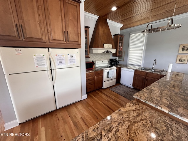 kitchen featuring white appliances, wood finished floors, a sink, ornamental molding, and custom exhaust hood