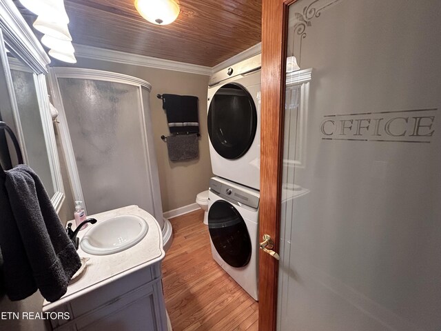 laundry room featuring stacked washer / dryer, sink, crown molding, and light hardwood / wood-style flooring