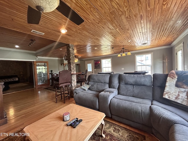 living room with a fireplace, visible vents, ornamental molding, wood finished floors, and wooden ceiling