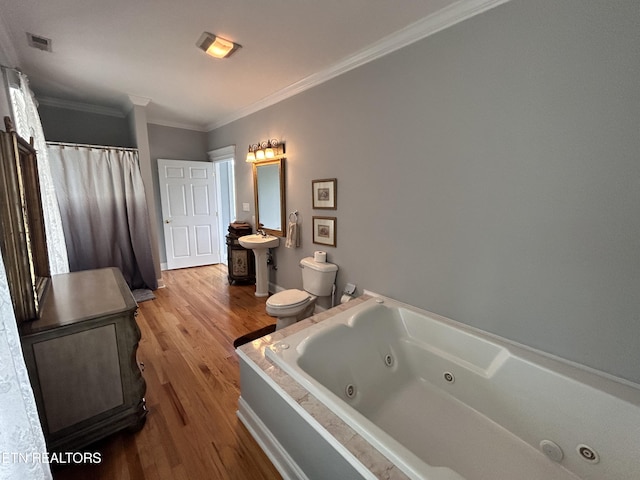 bathroom featuring visible vents, toilet, ornamental molding, wood finished floors, and a tub with jets