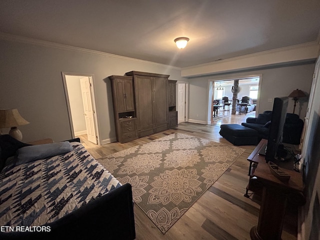 bedroom with ornamental molding, light wood-style flooring, and baseboards