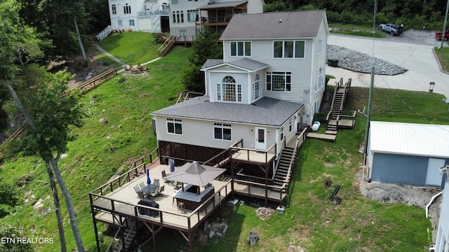 rear view of property featuring roof with shingles, a chimney, a lawn, stairway, and a deck