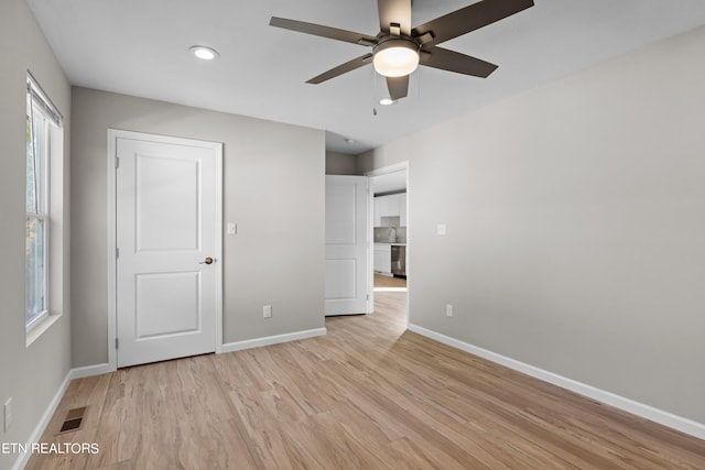 unfurnished bedroom featuring a ceiling fan, visible vents, light wood-style flooring, and baseboards