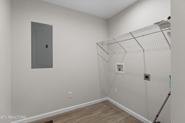 clothes washing area featuring electric panel, hookup for an electric dryer, hookup for a washing machine, and light wood-type flooring