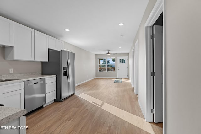 kitchen with appliances with stainless steel finishes, white cabinetry, light hardwood / wood-style flooring, and ceiling fan