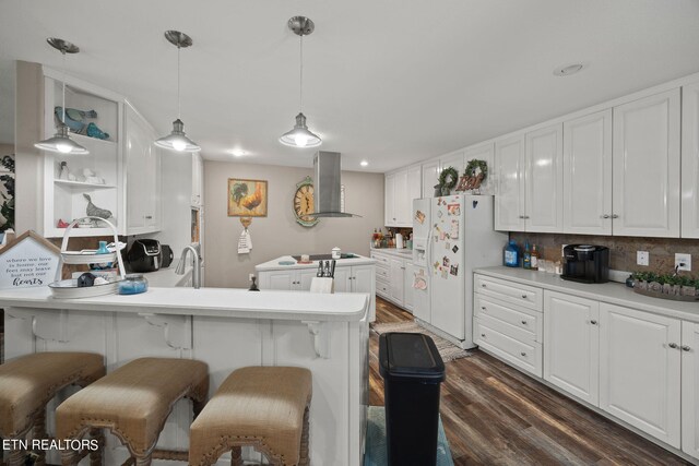 kitchen with wall chimney exhaust hood, dark hardwood / wood-style flooring, a breakfast bar, kitchen peninsula, and white fridge with ice dispenser